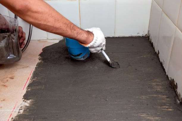 a person using a brush to put cement on the floor